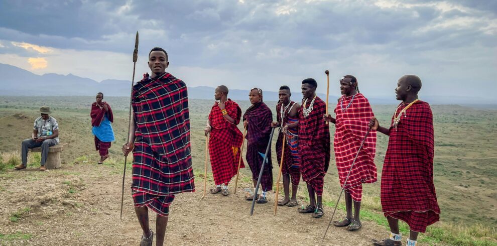 8-Day Tanzania Safari & Zanzibar Experience A group of Maasai men in colorful traditional garments in the scenic landscapes of Arusha, Tanzania.