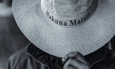 Black and white portrait of a person in a Hakuna Matata hat, capturing a serene safari vibe.