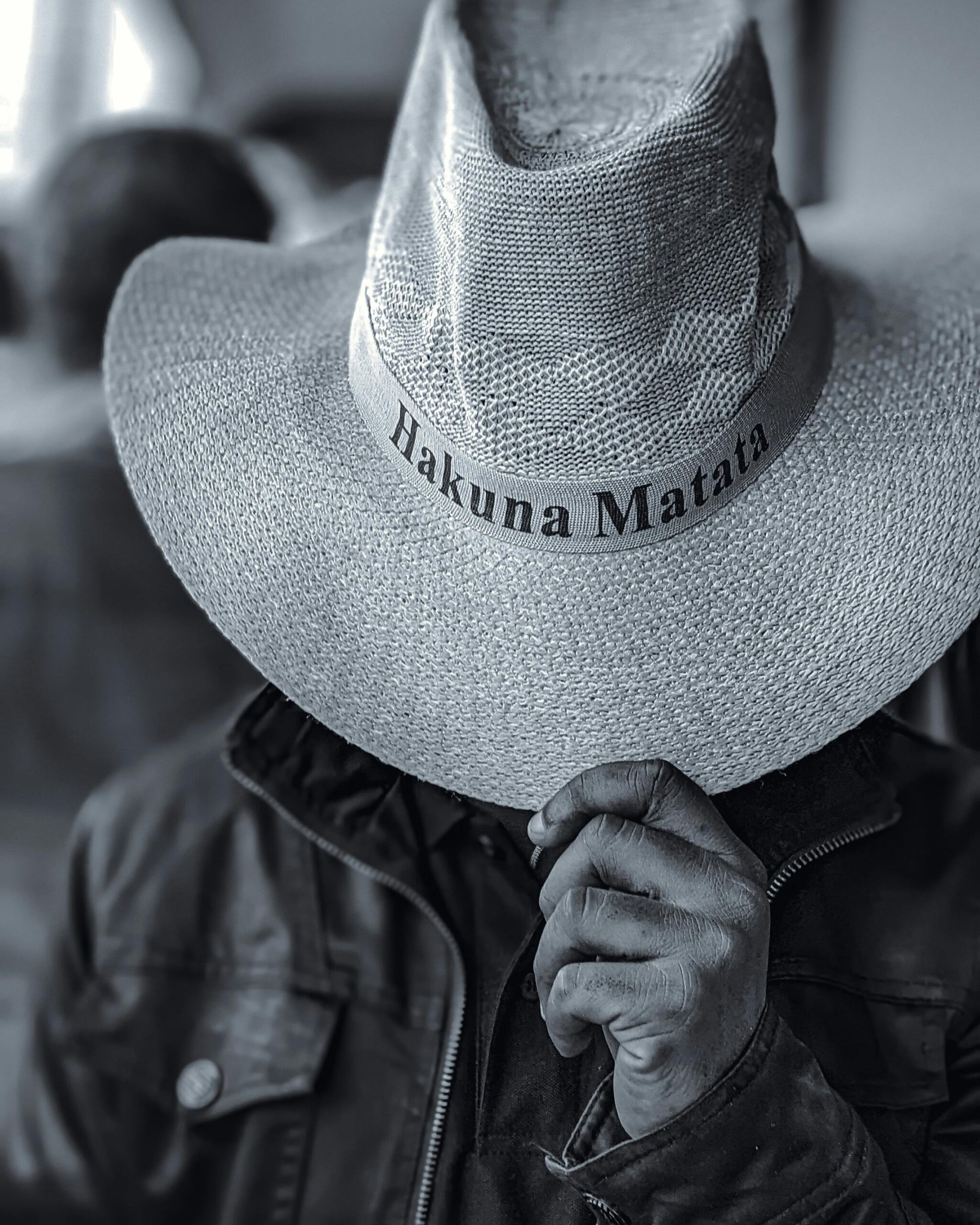 Black and white portrait of a person in a Hakuna Matata hat, capturing a serene safari vibe.